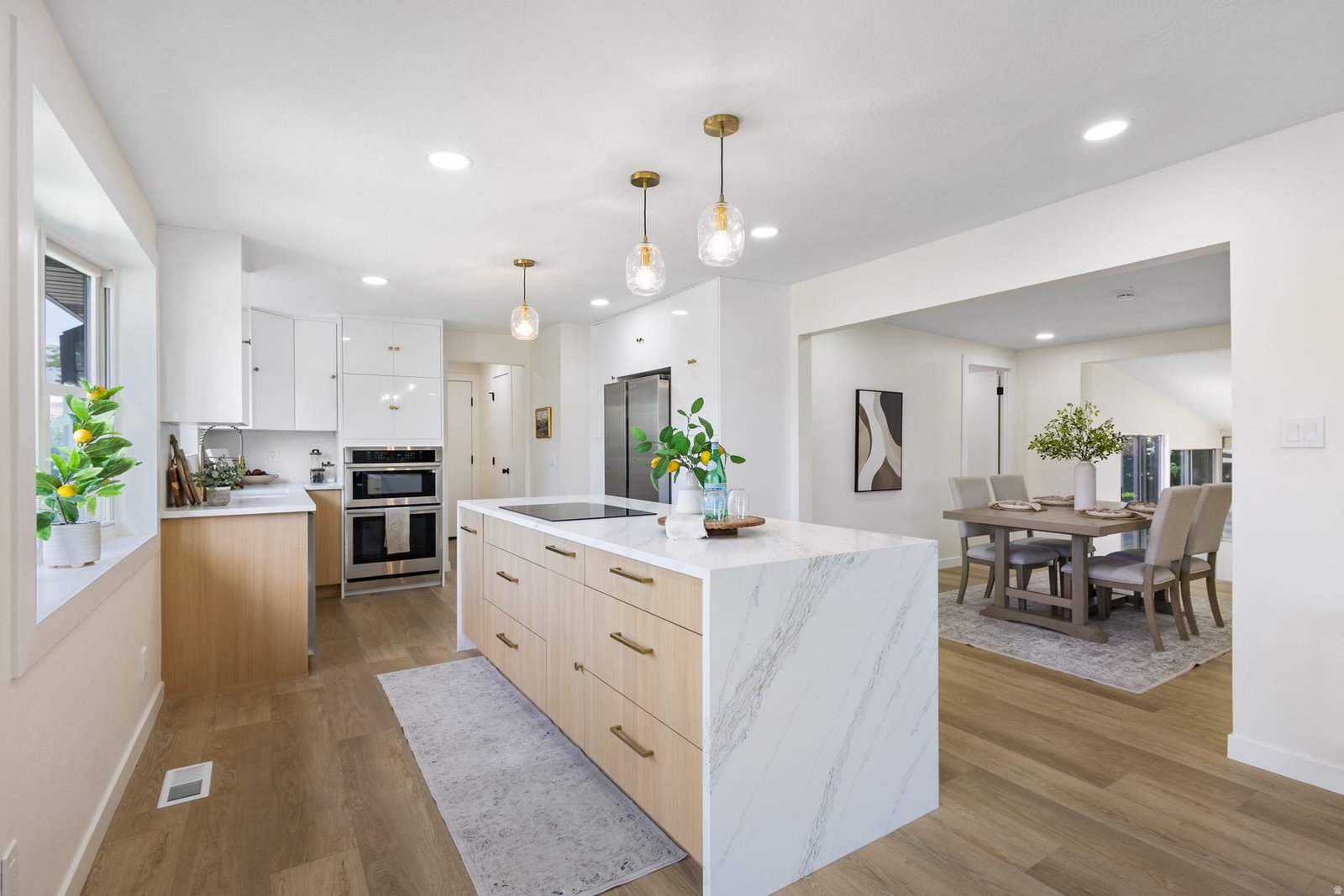 Bright white kitchen remodel with wood island, marble waterfall countertop and open dining area in Utah County